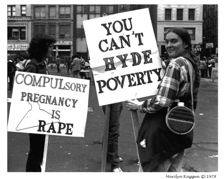 Protesters hold signs at a rally opposing the Hyde Amendment, including one that reads You can’t Hyde poverty and another that says Compulsory pregnancy is rape.