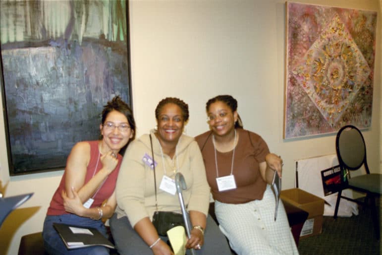 Three people with conference badges sit together and smile at an abortion funds gathering.